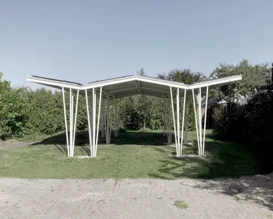 Seitliche Ansicht eines Stahlkonstruktes verbaut mit Solaranlagen im Hinterhof mit strahlend schönem blauen Himmel