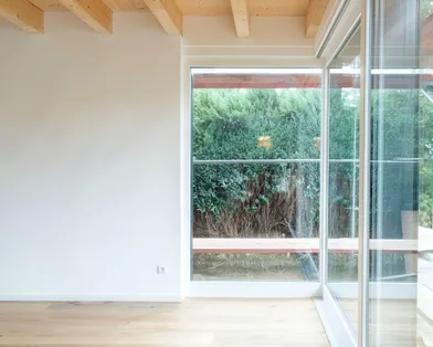 Innenansicht eines Raumes im fertigen Bauzustand eines Hauses mit Blick durch ein Fenster zum Garten
